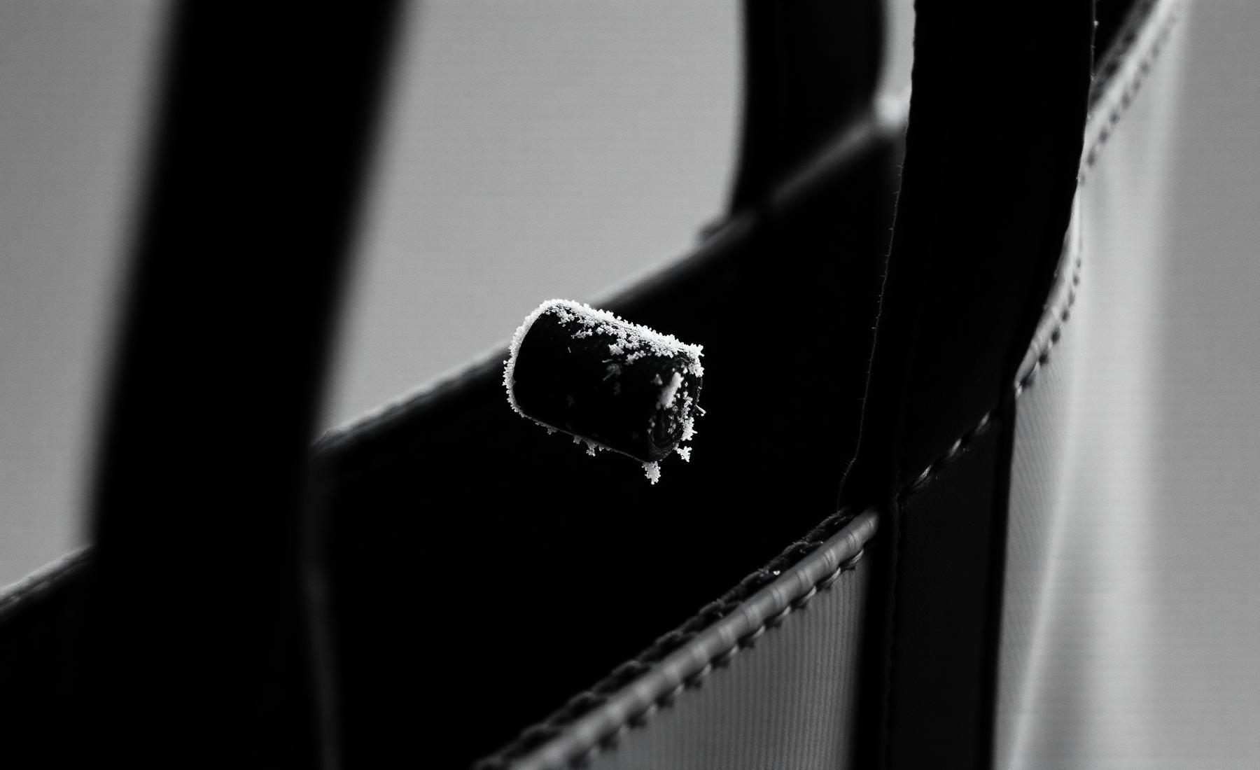 Monochrome close view of a tote bag handle pulled taut against snow